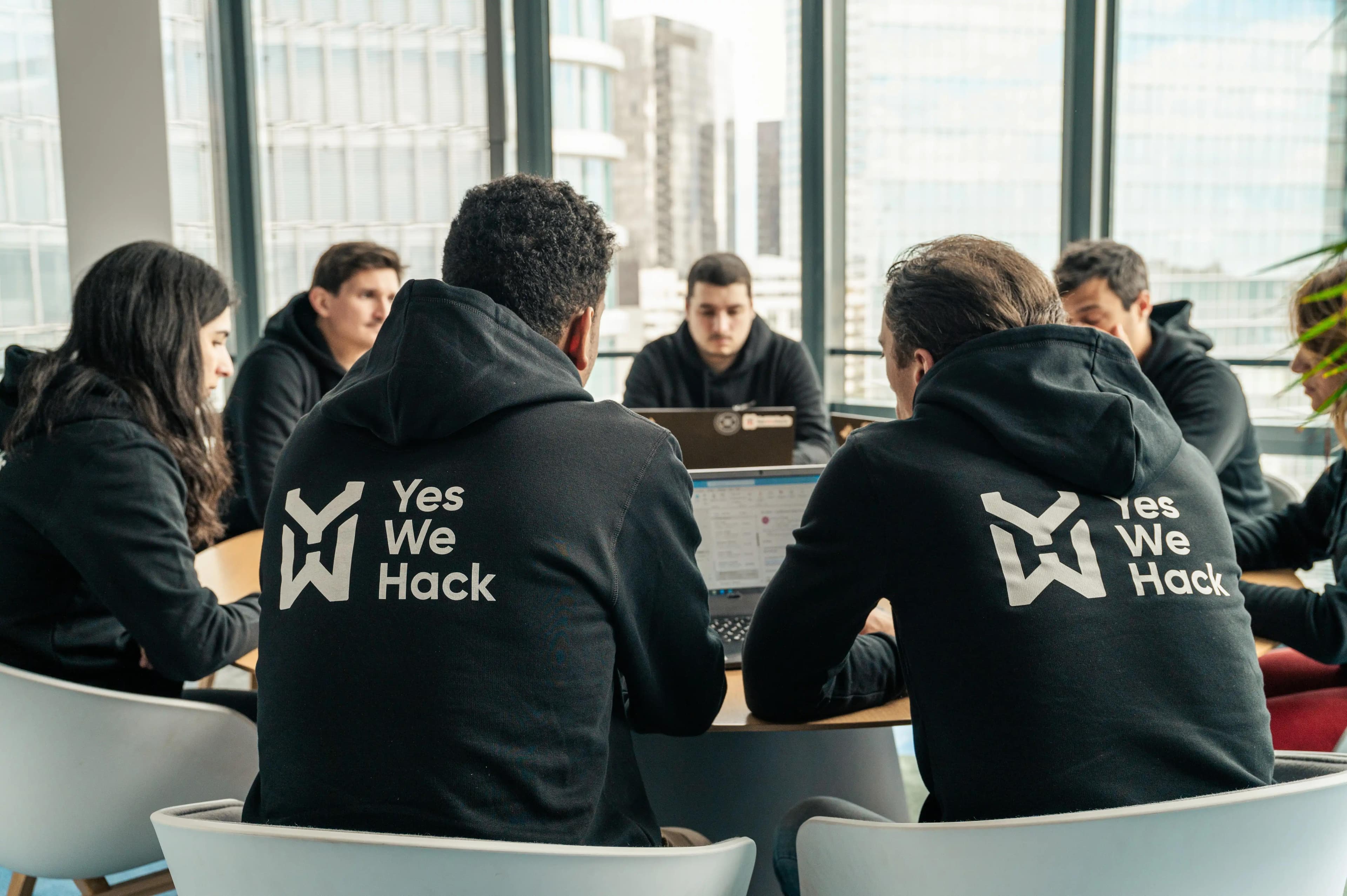 YesWeHack in-house cybersecurity triage team and engineers collaborating around an office table, providing dedicated SecOps support.