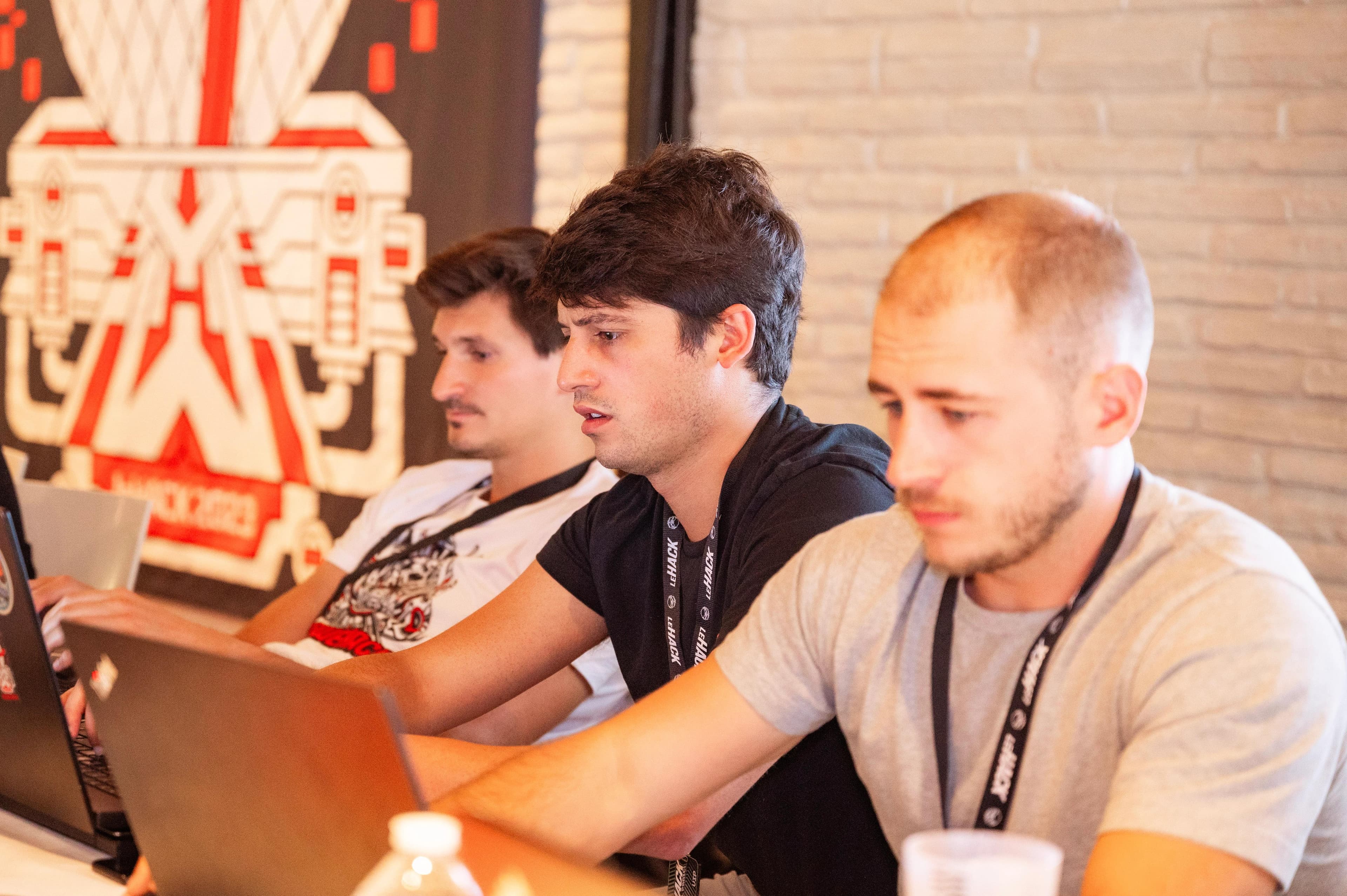 YesWeHack team members working side-by-side on laptops, representing the strategic partnership between the Triage team and Customer Success Managers.